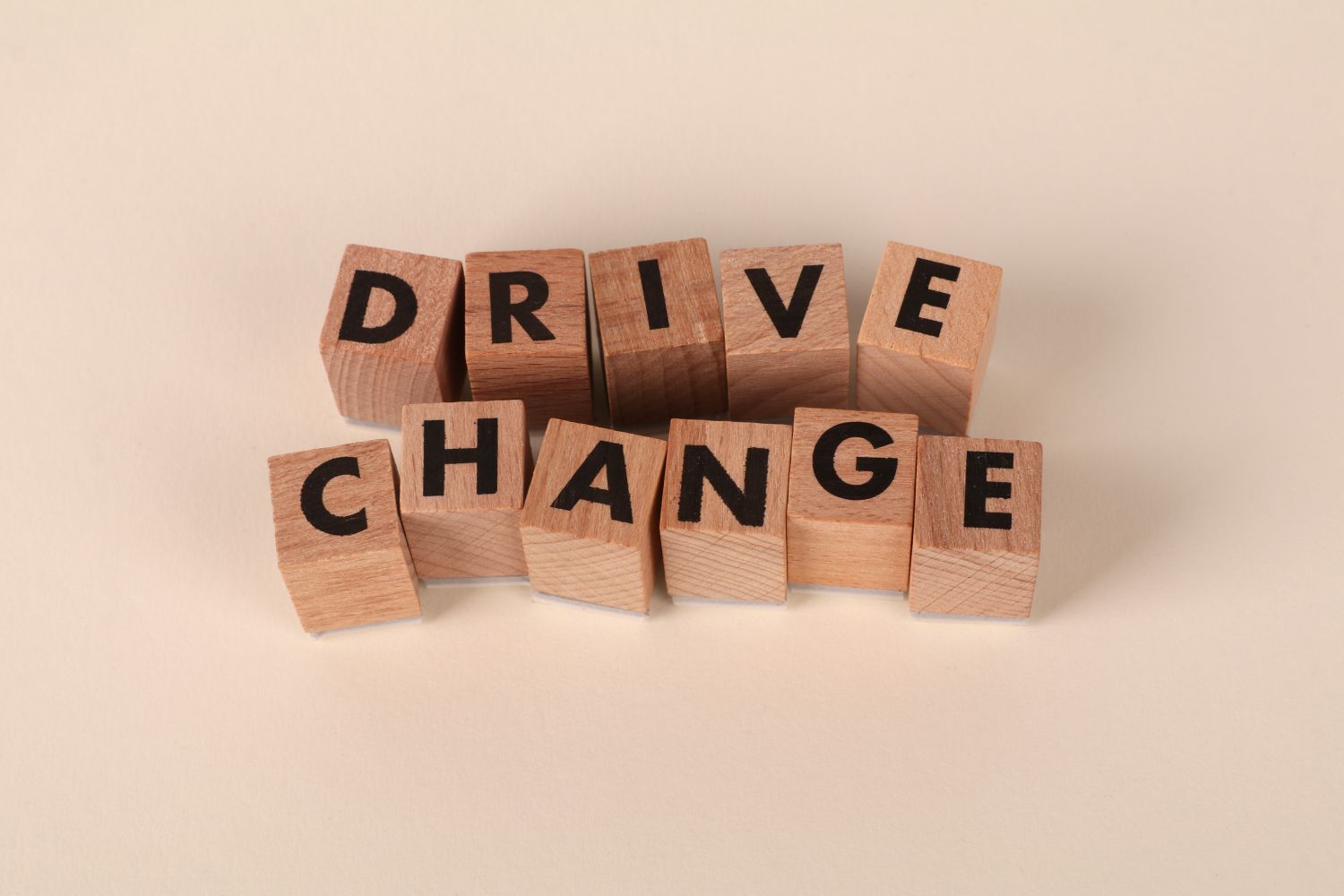 Wooden blocks spelling 'Drive Change' on a neutral background, symbolizing motivation and growth.