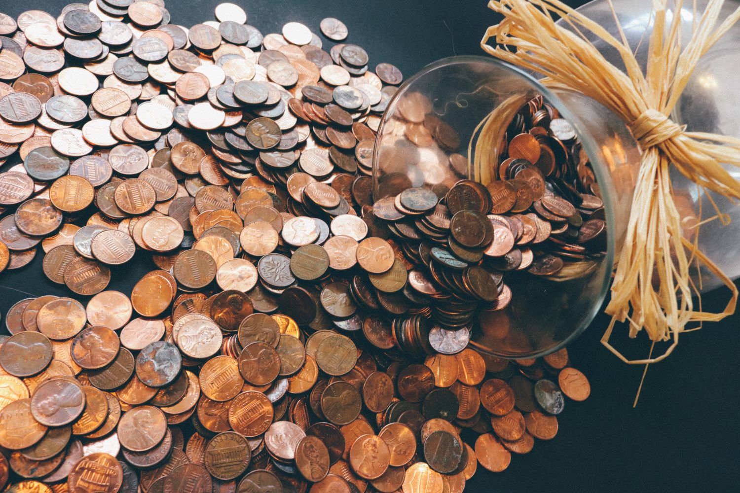 Spilled jar of pennies creating a pattern of coins representing savings and finance.