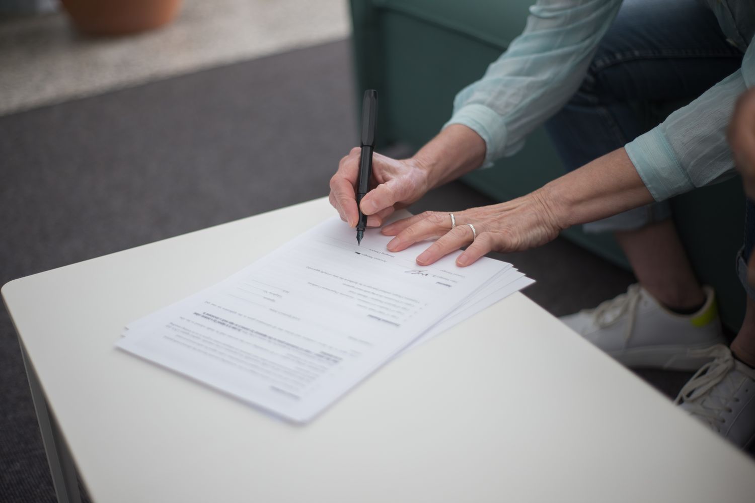 A person signing important legal documents on a table, emphasizing business and professionalism.